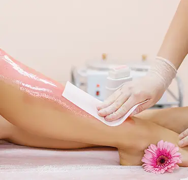 photo de jambes d’une femme dans un institut de beauté qui se fait épiler avec de la cire rose 