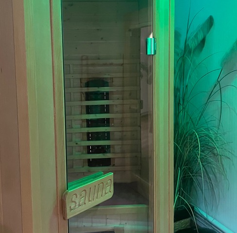 Photo de l’intérieur d’un sauna, des bancs en bois sont apparents à l’intérieur du sauna.